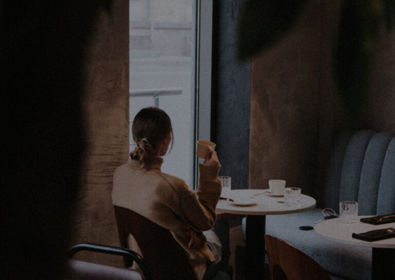 Eine Frau sitzt an einem Tisch und genießt einen leckeren FeinSinn Cafe.